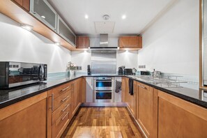 Cozinha moderna com armários de madeira, eletrodomésticos de aço inoxidável e uma ilha central.