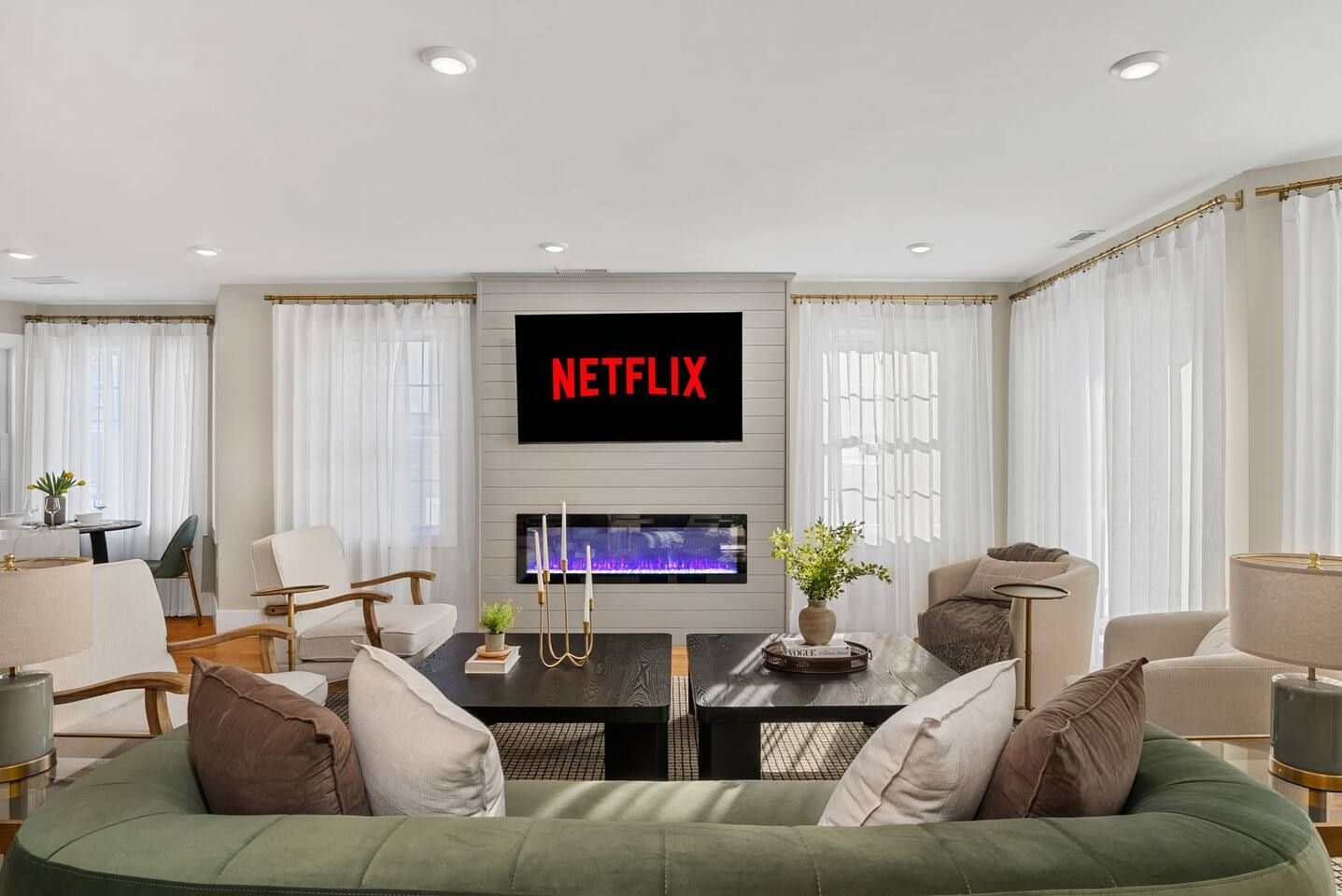 A modern living room with a fireplace, a flat-screen TV mounted above it, and a green sofa.