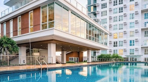 A modern building with a swimming pool, large windows, and a covered outdoor area.