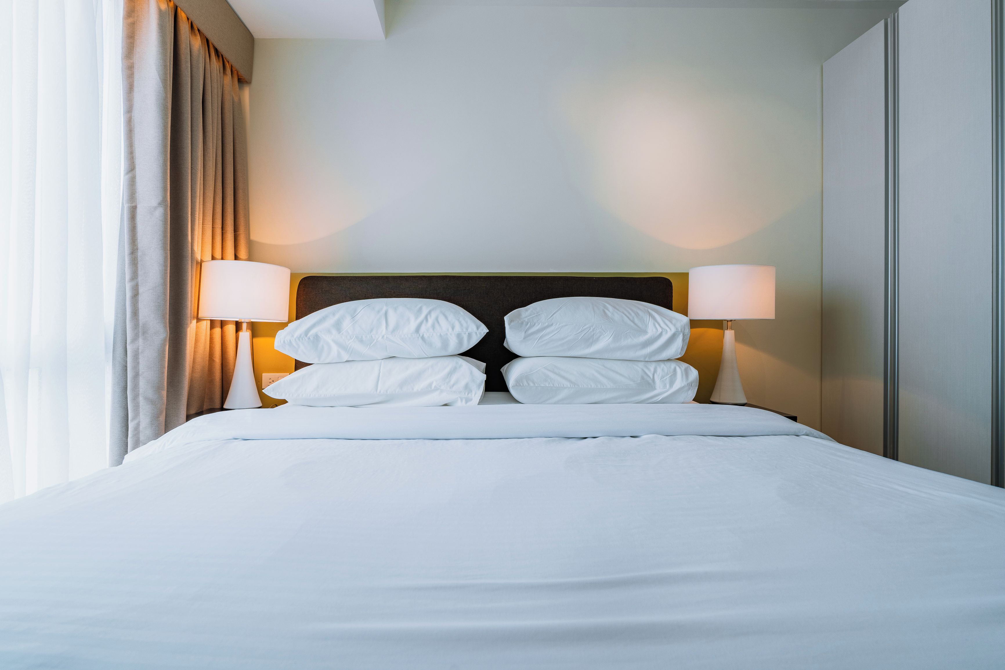A neatly made bed with white linens and two bedside lamps.