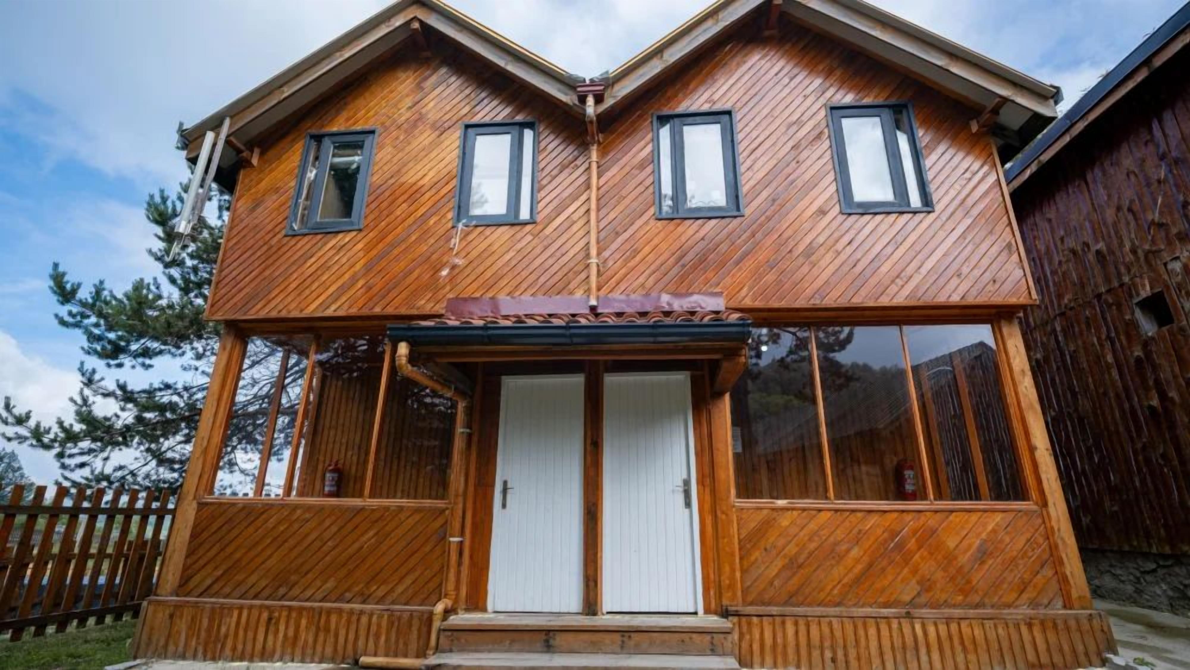 A two-story wooden house with a front porch, a garage, and a fenced yard.