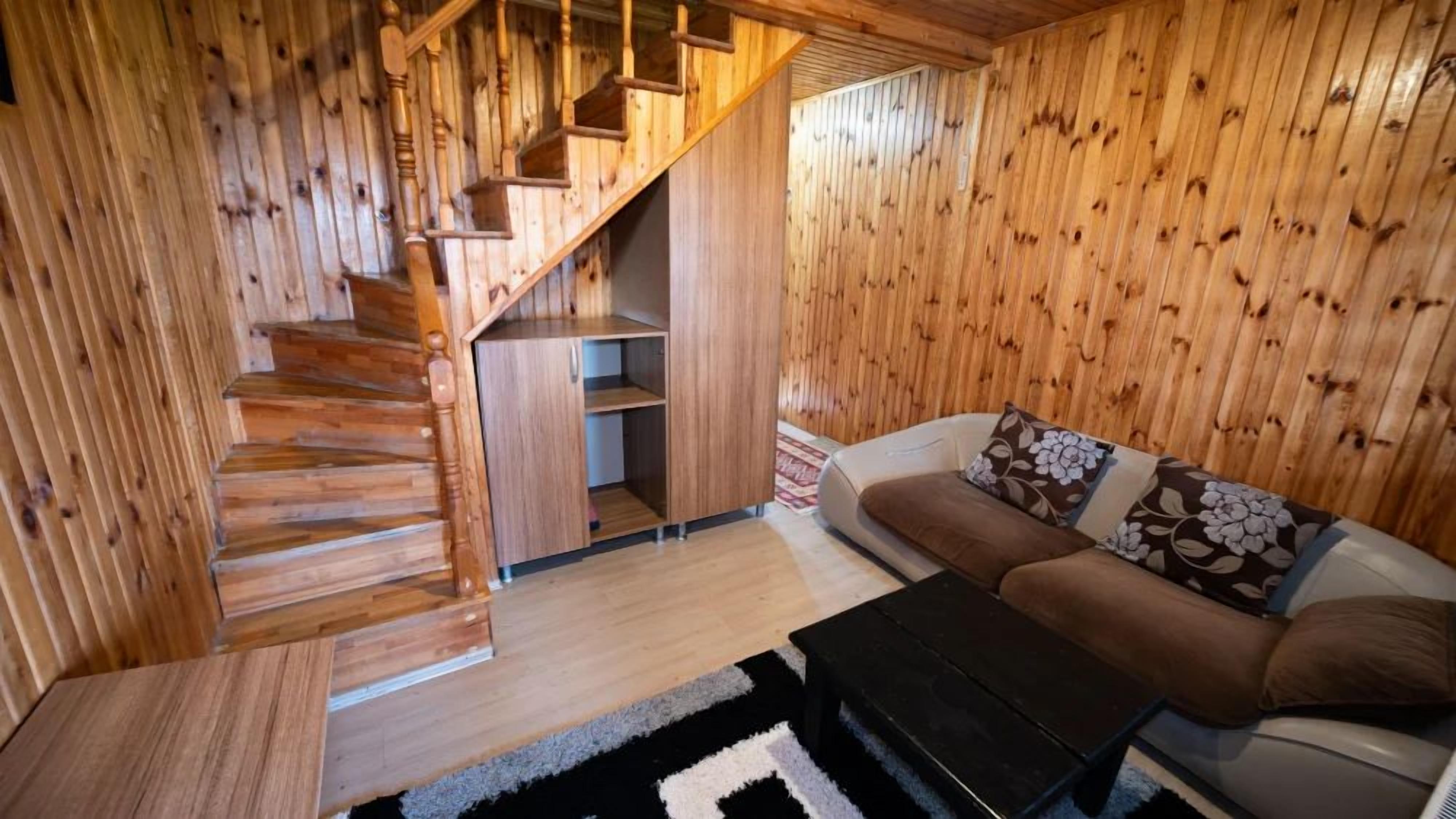 A wooden interior with a staircase, a sofa, and a coffee table.
