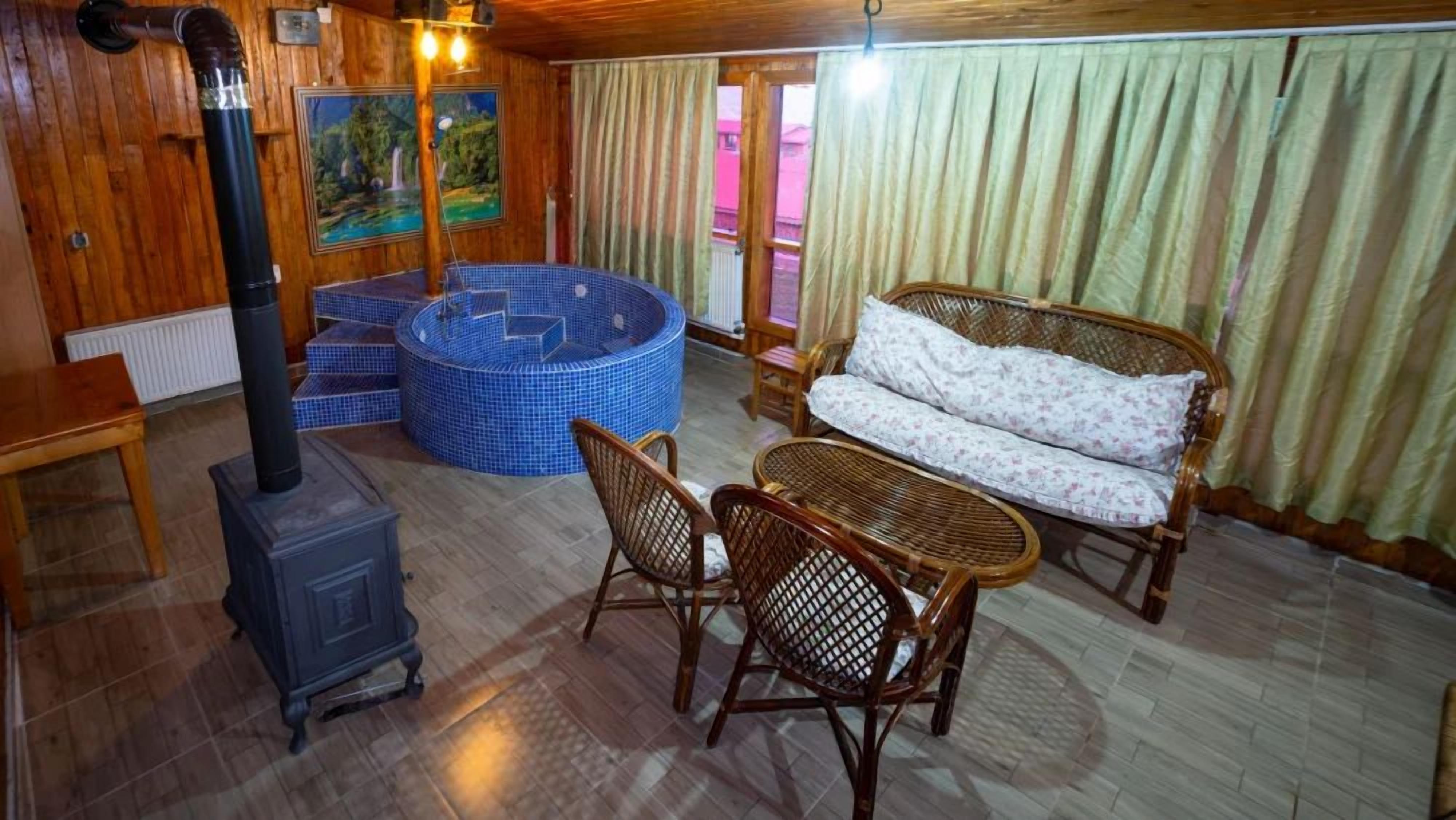 A cozy room with a wood-burning stove, a blue hot tub, wicker furniture, and a painting on the wall.