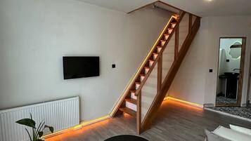 Una sala de estar moderna con una escalera de madera, una mesa de centro redonda negra y un sofá blanco.
