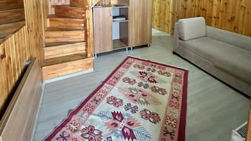 Un interior de madera con una escalera, un sofá y una alfombra estampada.
