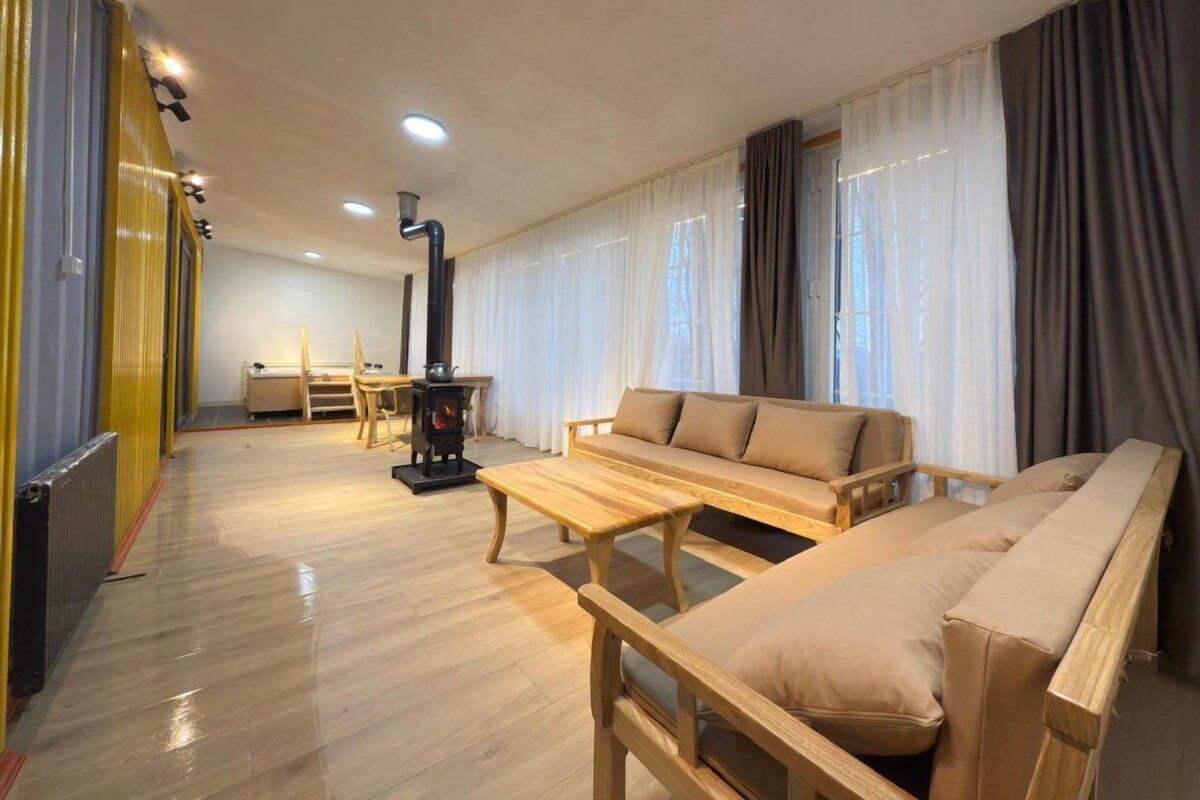 Een ruime woonkamer met een bank, een houten salontafel en een open haard.
