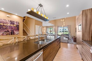 A modern kitchen with a central island, stainless steel appliances, and a hanging light fixture. - Luxury 3BR Villa w/ BBQ Near Disney (Kissimmee)