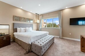 A bedroom with a large bed, a bench, a TV, and a window with curtains. - Luxury 3BR Villa w/ BBQ Near Disney (Kissimmee)