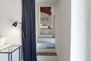 A staircase with white walls and a wooden ceiling, leading to a room with a bed and a lamp. - Hostdomus - Pool and Wine (Rosignano Monferrato)