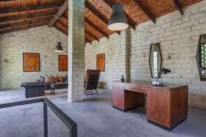 A rustic room with exposed brick walls, a wooden ceiling, a desk, a chair, and a sofa. - Hostdomus - Pool and Wine (Rosignano Monferrato)