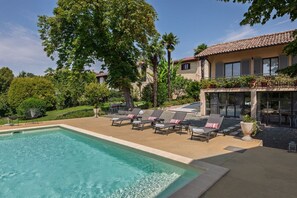 A swimming pool with lounge chairs and a building with a tiled roof. - Hostdomus - Pool and Wine (Rosignano Monferrato)