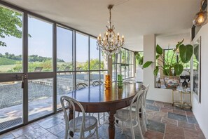 A dining area with a large table, chairs, a chandelier, and a view of the outdoors. - Hostdomus - Pool and Wine (Rosignano Monferrato)