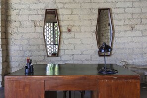 Et træbord med en sort lampe, et spejl og et vindue med et mønster.
