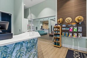 Ein moderner Empfangsbereich mit einer Theke, einer Sitzecke und einer Wand mit Hüten und Souvenirs.