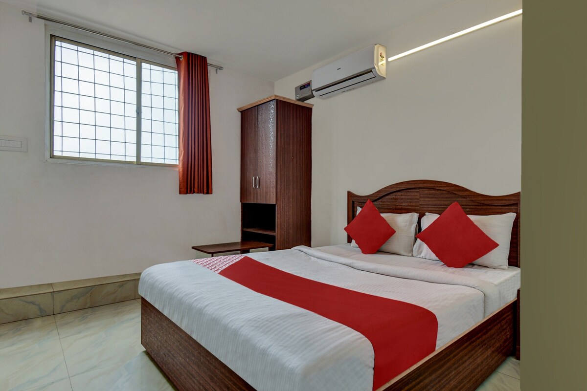 Een hotelkamer met een bed, een kledingkast, een raam met gordijnen en een airconditioning.