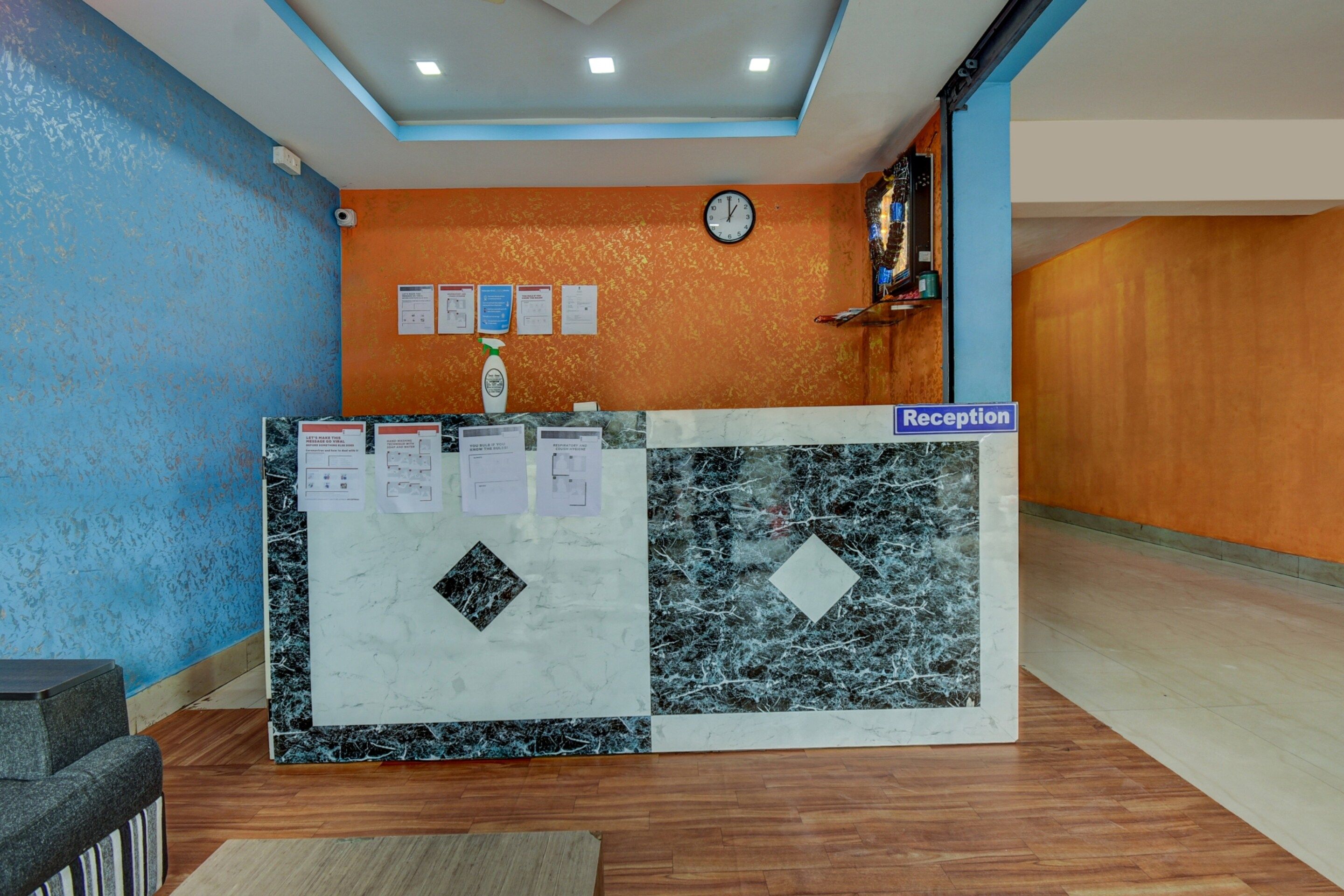 A reception desk with a clock, informational posters, and a sign indicating the reception area.