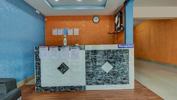 A reception desk with a clock, informational posters, and a sign indicating the reception area.