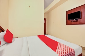 A hotel room with a bed, a flat-screen TV mounted on the wall, and a door leading to another room. - Hotel O K N Residency (Bengaluru)