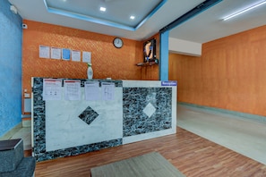 A reception desk with a clock, informational posters, and a sign indicating the reception area. - Hotel O K N Residency (Bengaluru)