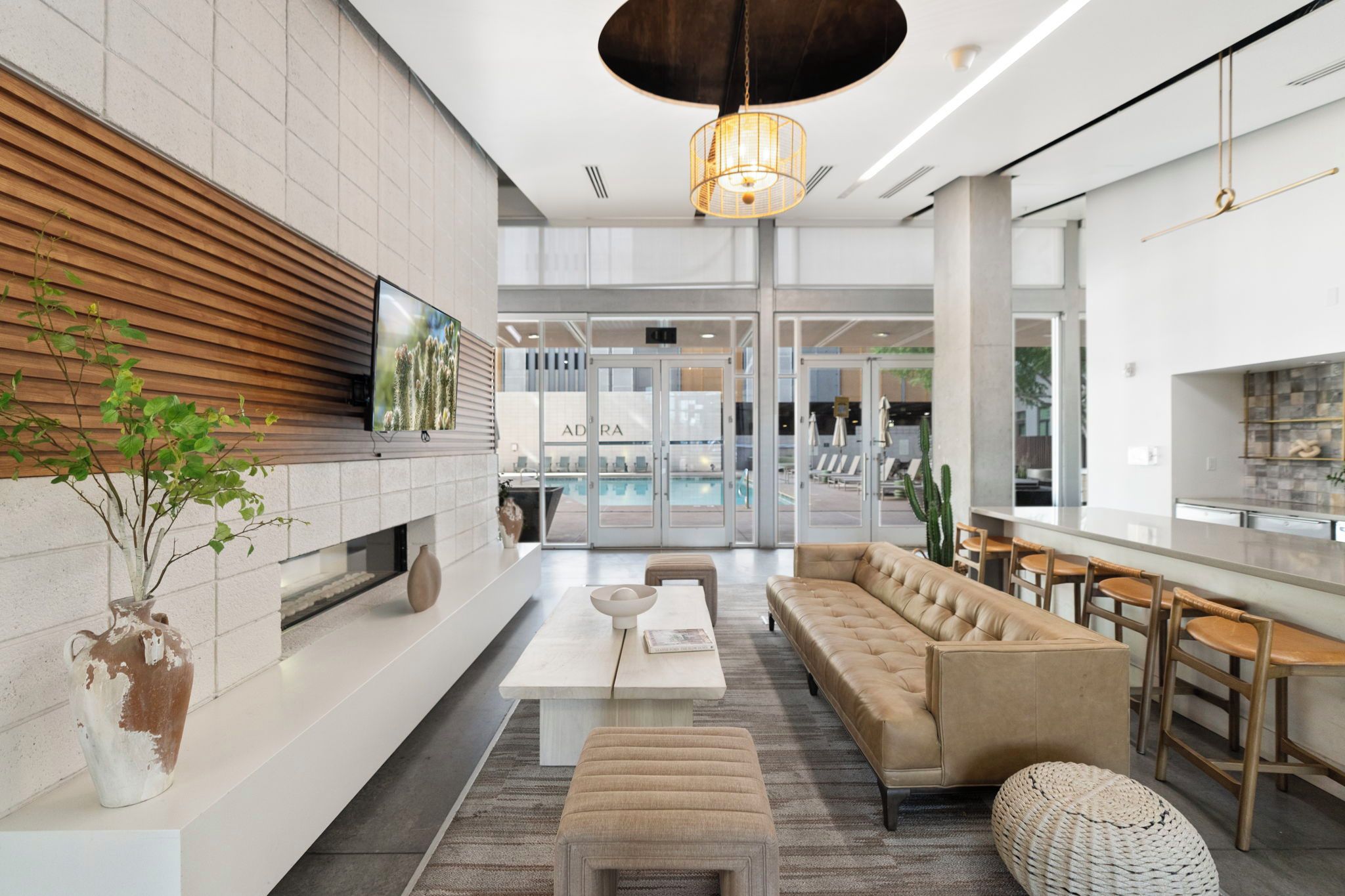 Un interior moderno con sofá, zona de comedor, televisor y piscina.