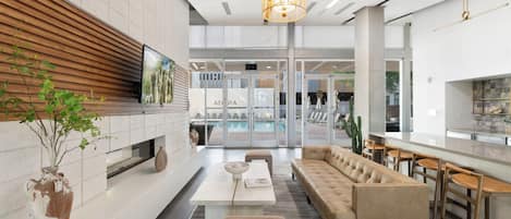 Un interior moderno con sofá, zona de comedor, televisor y piscina.
