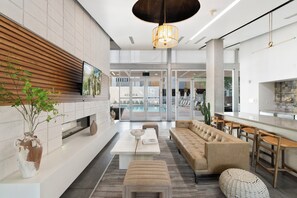 A modern interior with a sofa, a dining area, a television, and a pool area. - Chic 2BR | Pool | W/D | Wi-Fi Near Arts District (Phoenix)