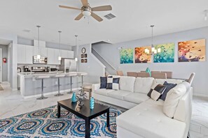 Un saló modern amb un sofà blanc, una taula de centre i una catifa amb dibuixos.