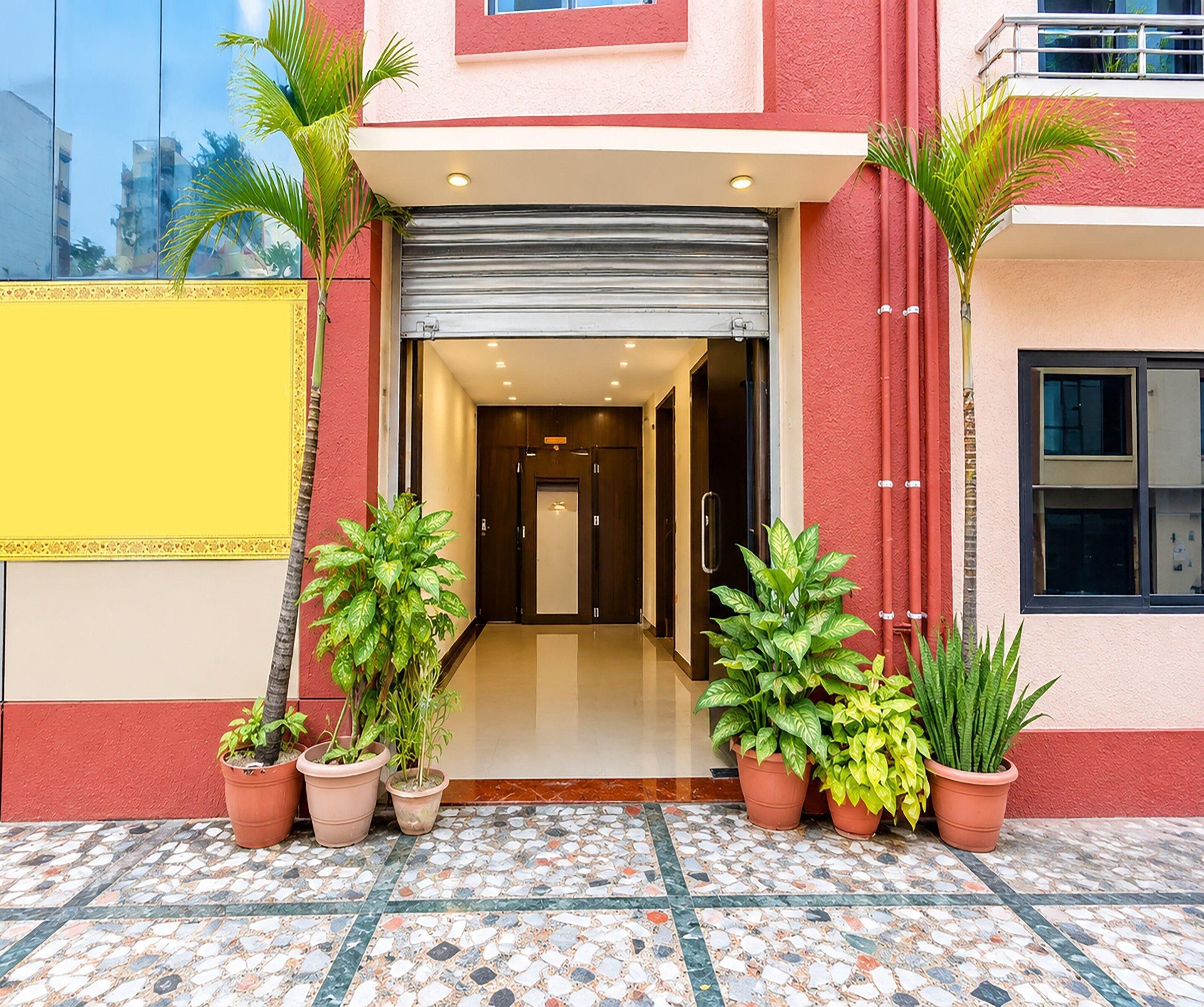 A hotel entrance with a tiled floor, potted plants, and a closed garage door.