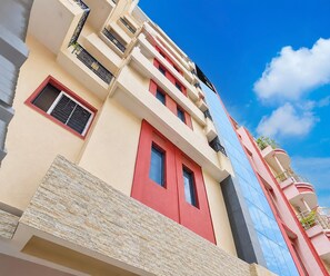 Ein mehrstöckiges Gebäude mit Balkonen, einer roten Tür und einer blauen Fassade.