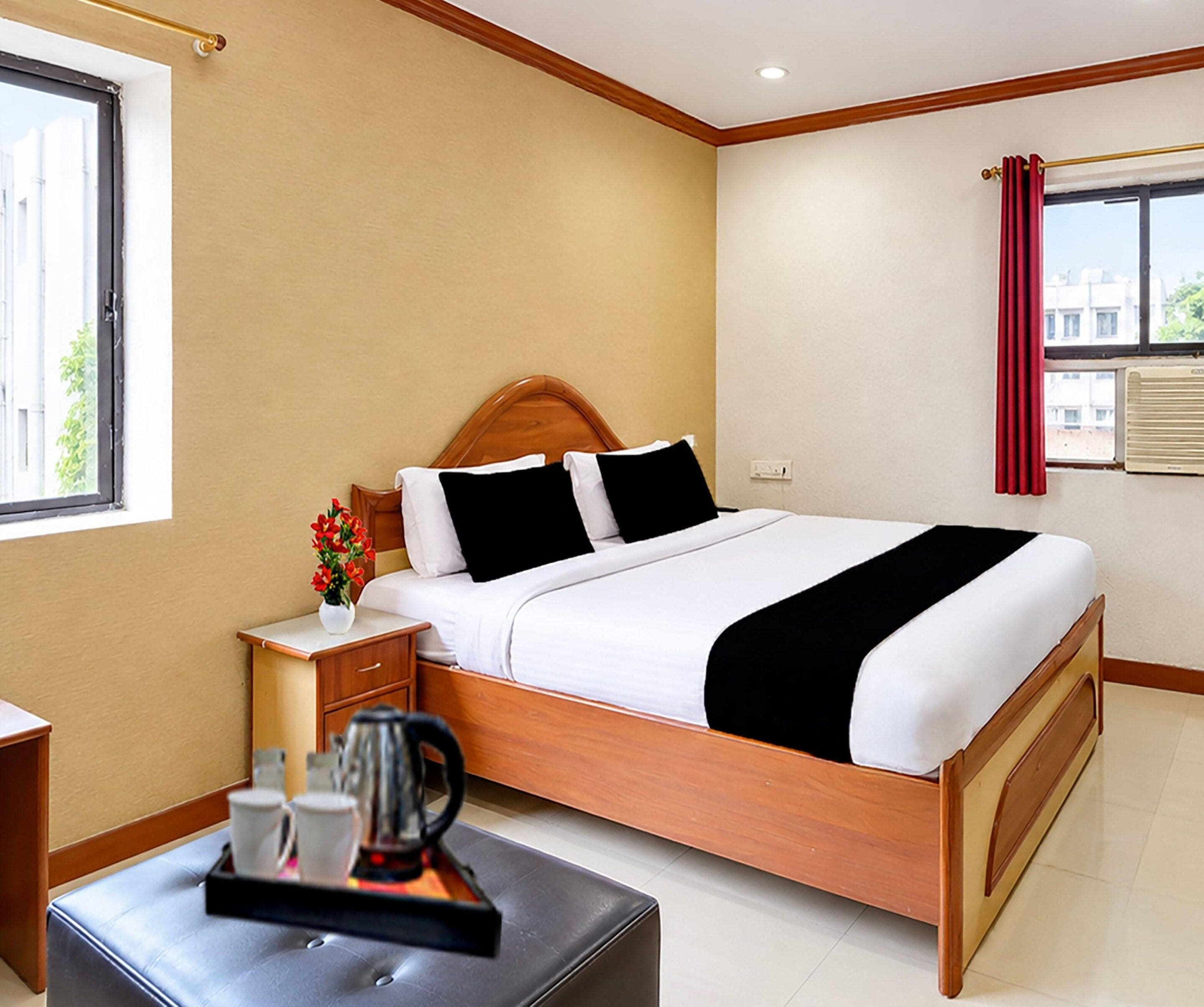 A hotel room with a bed, a nightstand, a coffee table, and a window with curtains.
