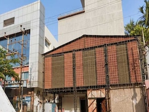 A building with a modern facade, a visible entrance, and a construction site with scaffolding. - Classic Hotel Sika Inn (Puducherry)