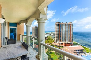 A balcony with a view of a beachfront resort, including high-rise buildings and a swimming pool. - Portofino Island Resort 2-1508 (Pensacola Beach)