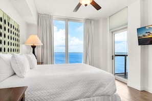 A hotel room with a large bed, a ceiling fan, a view of the sea, and a painting on the wall. - Portofino Island Resort 2-1508 (Pensacola Beach)