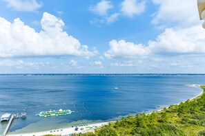 A coastal view with a clear sky, a sandy beach, and a boat docked at a pier. - Portofino Island Resort 2-1508 (Pensacola Beach)