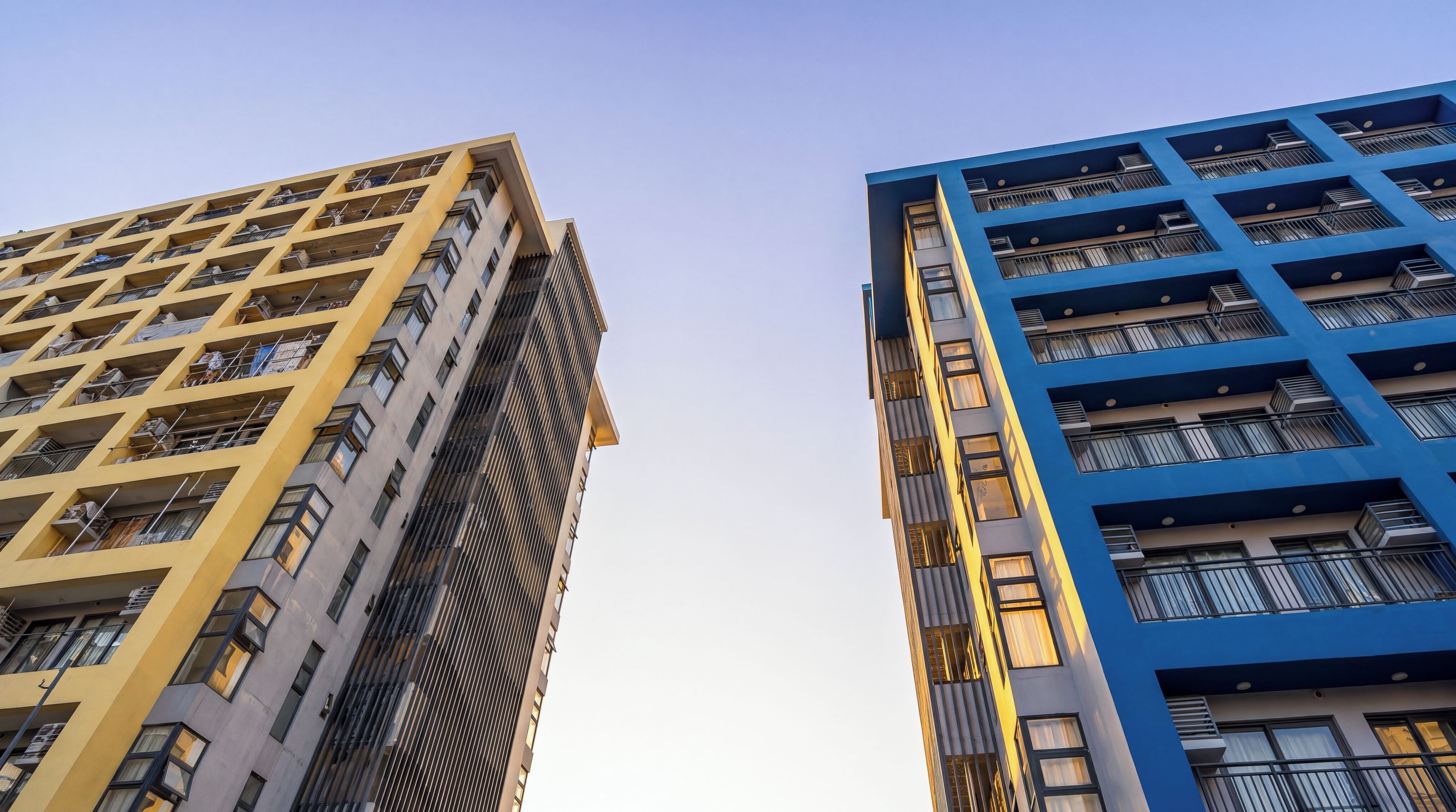 Dos edificios altos con un diseño arquitectónico moderno, con balcones y grandes ventanales.