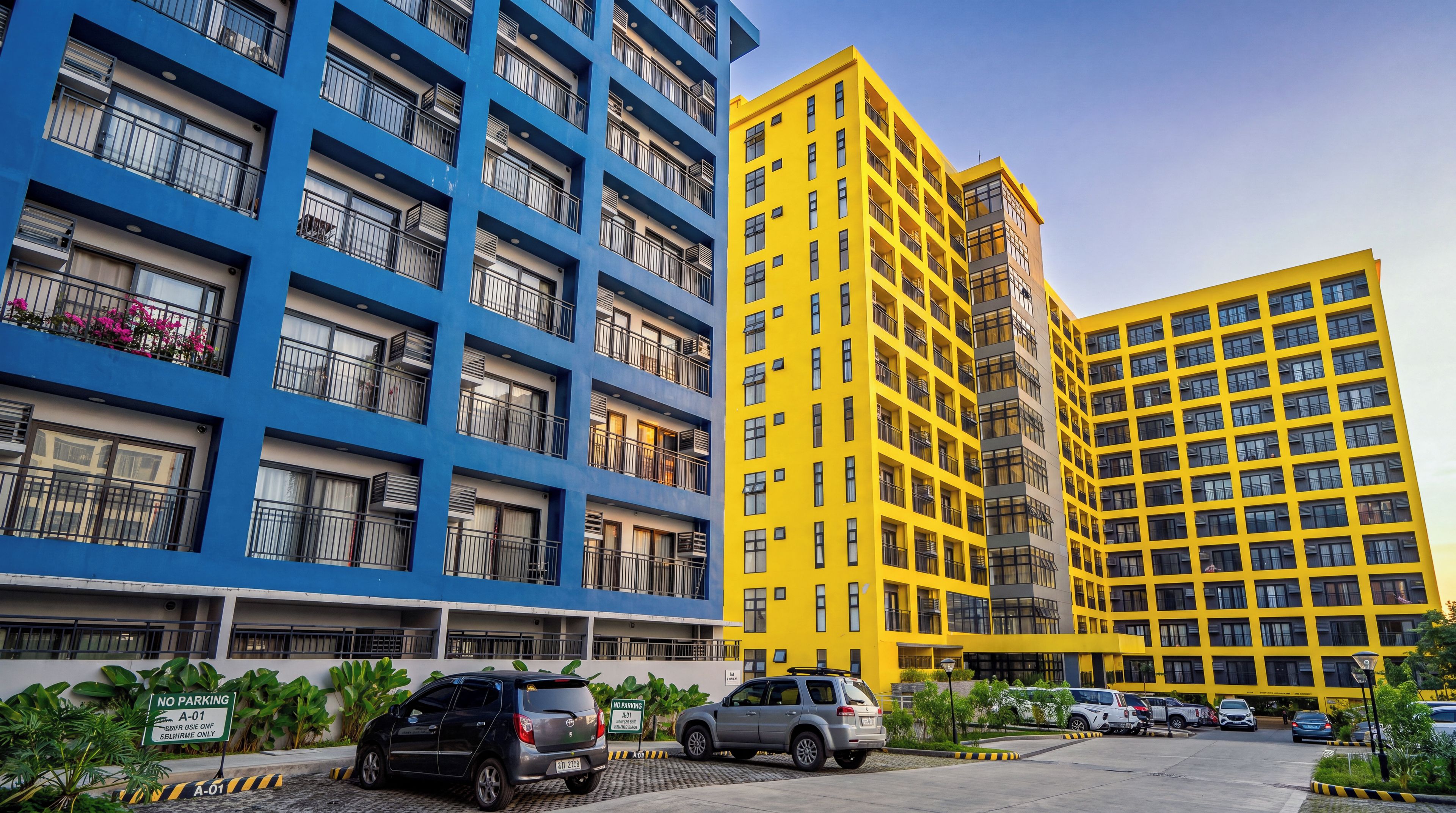 A multi-story residential building with balconies, a parking area, and a 'NO PARKING' sign.