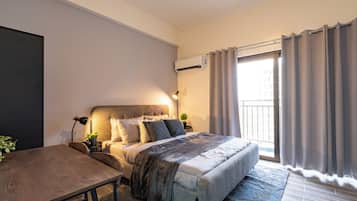 A modern bedroom with a bed, bedside table, lamp, and an air conditioning unit.