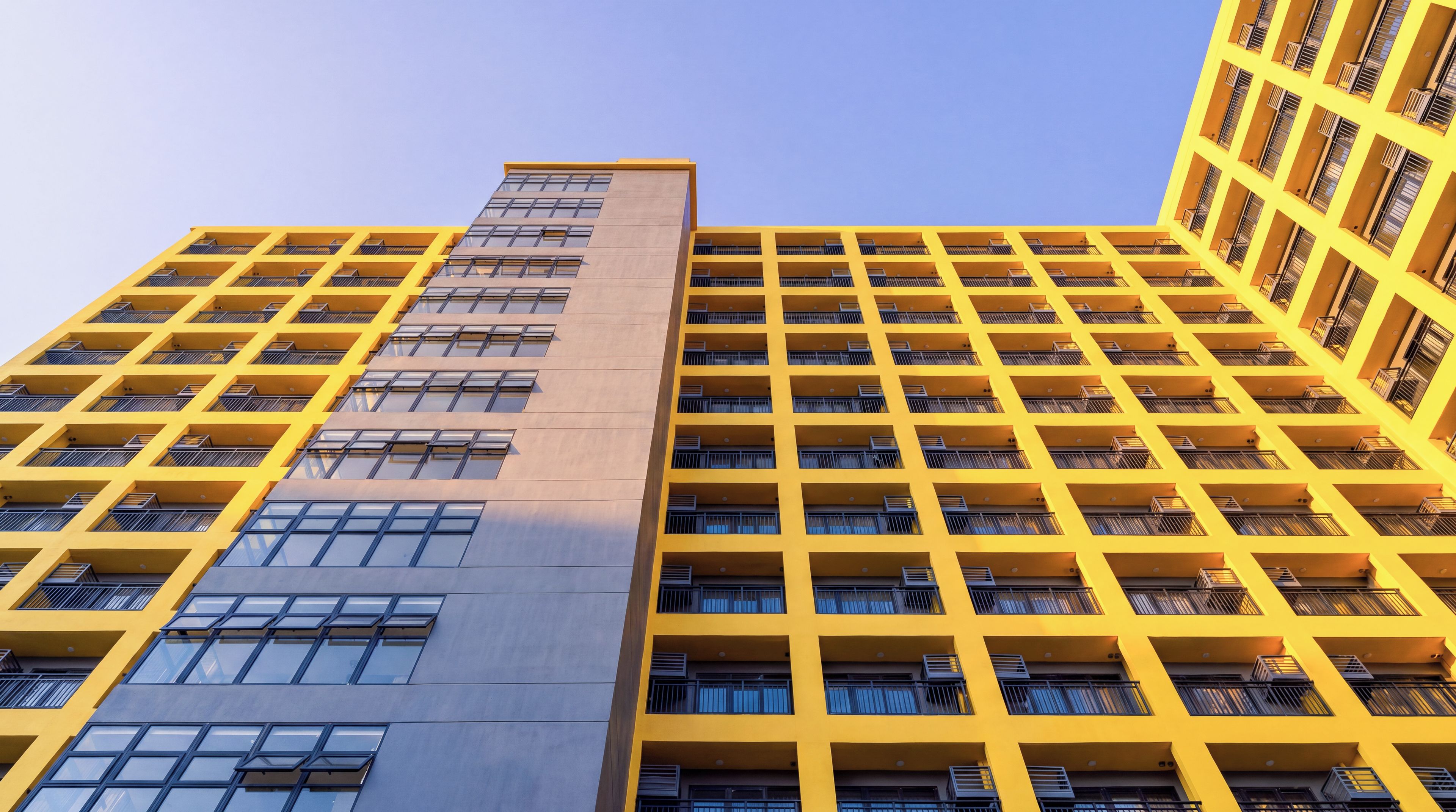 Un edificio alto con fachada amarilla y varios balcones.