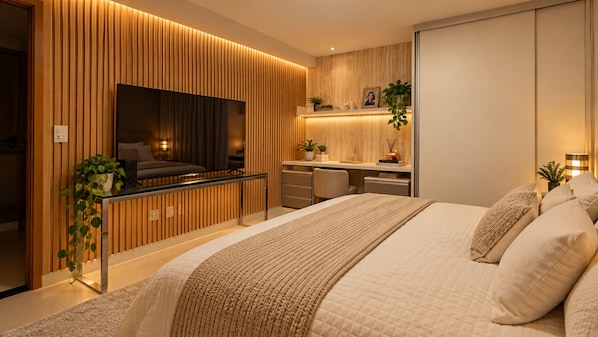 A modern bedroom with a large bed, a desk, and a TV.