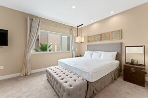 A bedroom with a large bed, a window with curtains, a flat-screen TV, and a bedside table with a lamp. - Magic Village 8guests Jacuzzi 8 min Disney (Kissimmee)