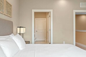 A hotel room with a bed, a nightstand with a lamp, a door leading to a bathroom, and a closet. - Magic Village Charming Special 6 min Disney (Kissimmee)