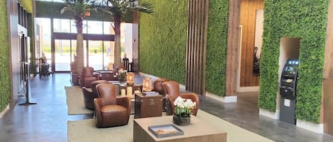 A lobby with a green wall, leather chairs, a coffee table, and a reception desk.