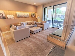 A modern living room with a sofa set, a glass-top coffee table, and artwork on the wall. - Magic Village 3 Suites Jacuzzi 6min Disney (Kissimmee)