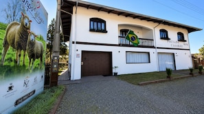 A building with a white facade, multiple windows, and a balcony. - Pousada Casarão - House in the Mountains: Fireplace, soccer field and animals. (Campo Alegre)