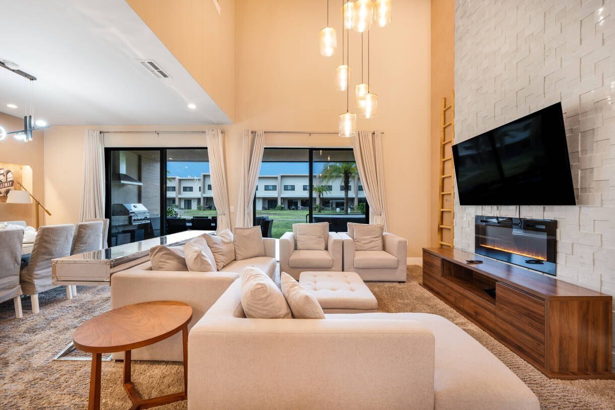 A modern living room with a large flat-screen TV, beige sofas, and a wooden entertainment unit.