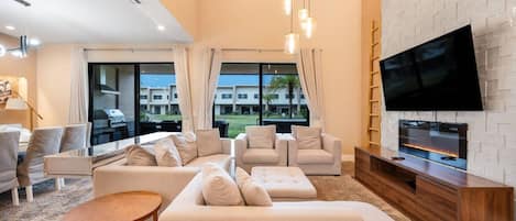 A modern living room with a large flat-screen TV, beige sofas, and a wooden entertainment unit.