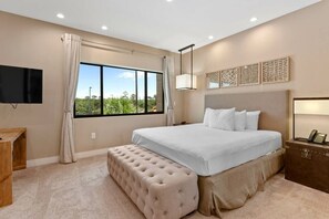 A bedroom with a large bed, a bench, a TV, and a window with a view of greenery. - Magic Village 3BR w/ Jacuzzi & BBQ Near Disney (Kissimmee)