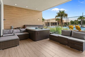 A modern outdoor lounge area with a hot tub, wicker furniture, and a view of a swimming pool. - Magic Village 3BR w/ Jacuzzi & BBQ Near Disney (Kissimmee)