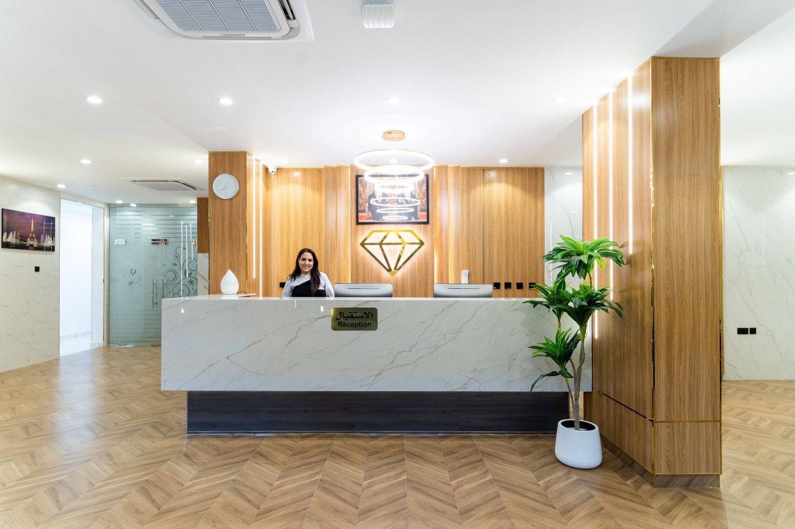 A reception desk with a marble top, wooden paneling, and a potted plant.