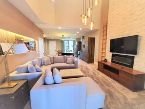 A modern living room with a sectional sofa, a flat-screen TV, and a wooden entertainment unit. - Magic Views Excellent 4suites Near 192/disney (Kissimmee)